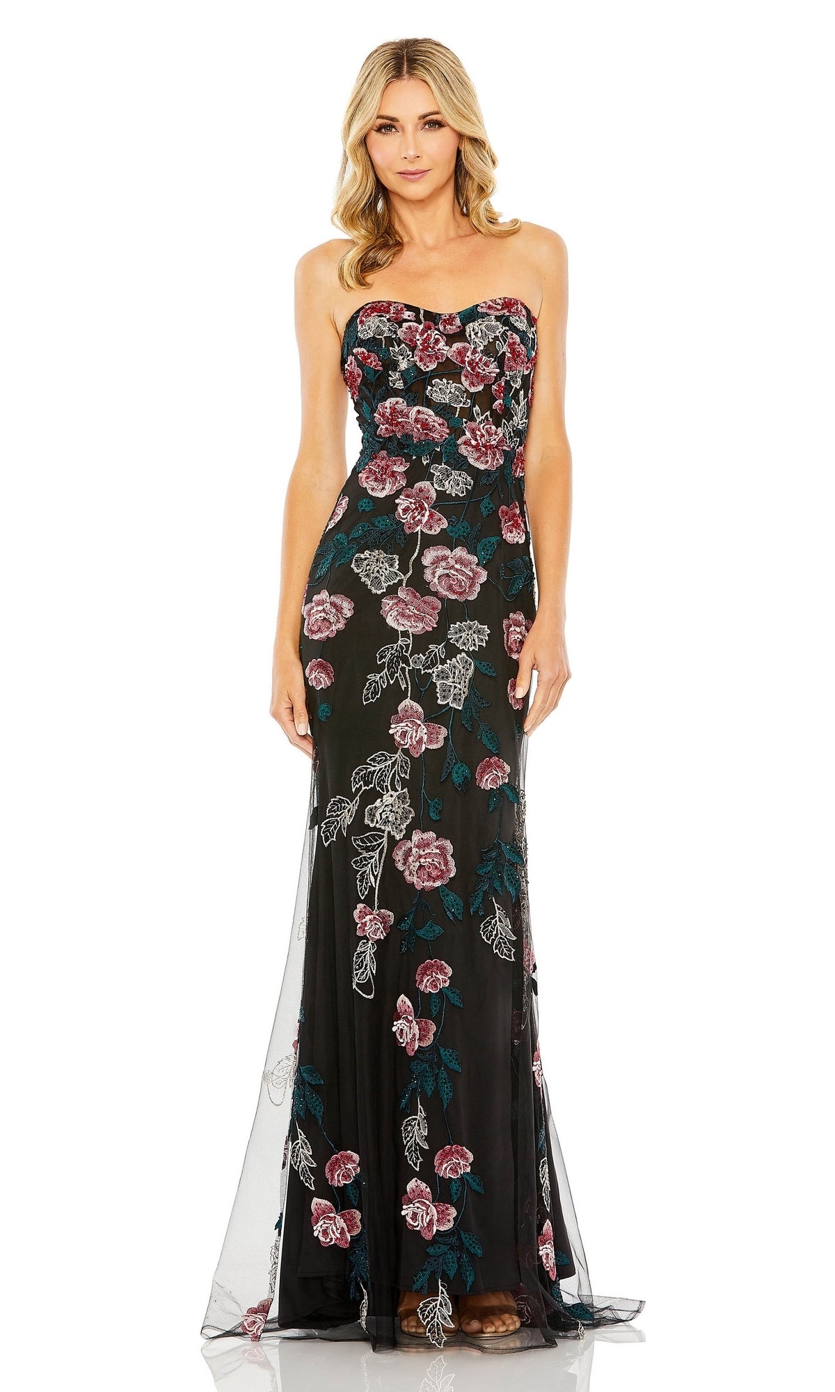 A woman wears the Long Formal Dress 20581 by Mac Duggal, featuring a strapless design, pink and green floral embroidery, a fitted waist, and sheer floor-length fabric.